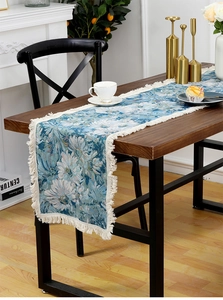 Detail of floral tapestry table runner with fringe tassels on dark wood dining table