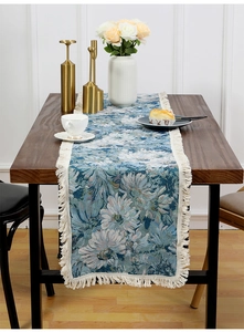 Detailed texture of jacquard fabric table runner with blue dahlias and cream tassels