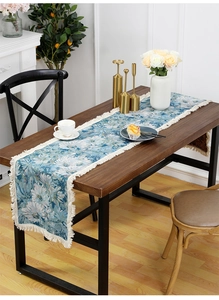 Close-up of retro floral table runner featuring white daisies and elegant cream tassels