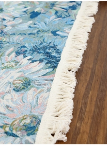 Close-up of blue floral jacquard table runner featuring elegant white fringe tassels