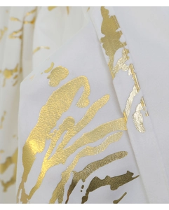 Detailed macro view of white velvet fabric with luxury gold foil stamping pattern
