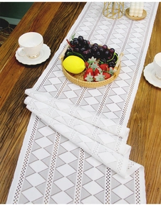 Close-up detail of white geometric hollow lace table runner with modern crochet texture