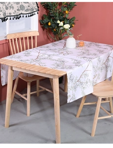 Detail of cotton linen tablecloth with floral leaf patterns and birds on a wooden table