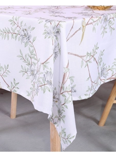 Detail of botanical print on cotton linen tablecloth featuring birds and green leaves