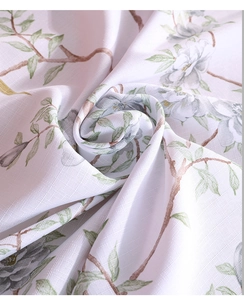 Close-up of linen-textured tablecloth with elegant white floral and green leaf printing