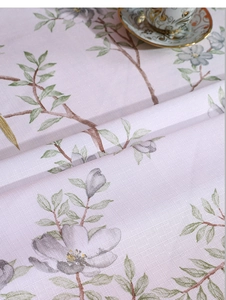 Close-up of floral linen tablecloth featuring soft pink tones and vintage teacup