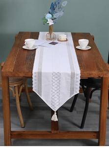 Detailed view of white woven lace table runner with hollow patterns and elegant tassels