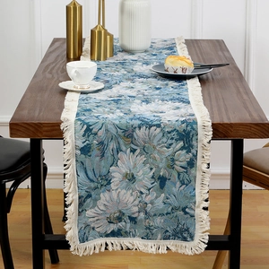 Vintage jacquard table runner with blue floral patterns and tassels on a wooden table