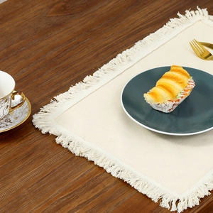 Nordic cream linen place mat with fringe on a wooden table for dining room decor