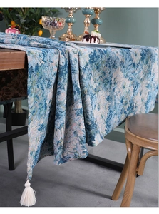 Detailed texture of blue jacquard table runner with decorative cream tassels on wood