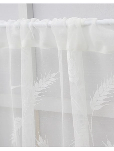 Close-up of white lace curtain with wheat embroidery showing delicate mesh texture