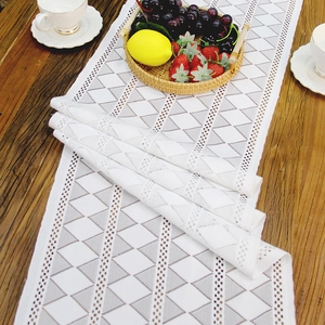 Nordic white lace table runner with geometric triangle mesh on a wooden dining table