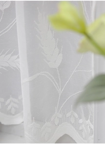 Detail of white lace curtain showing intricate floral patterns and wavy scalloped edge detail