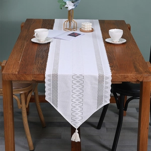 French lace white table runner with hollow geometric patterns and elegant tassel accents