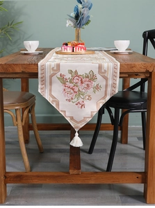 Detailansicht der klassischen Blumenstickerei und weißen Seidenquaste am Tischläufer