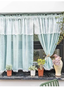 Detail of mint green lace cafe curtain with floral embroidery and white pom-pom trim