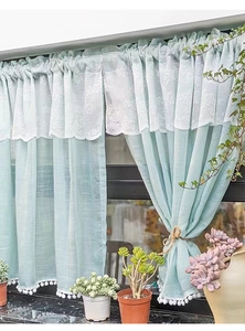 Detail of mint green velvet curtains with white lace floral overlay and pompom trim