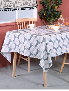 Close-up of blue-grey hexagonal pattern tablecloth on wooden table with green plants