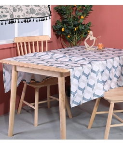 Detail of blue and white 3D geometric cotton linen tablecloth on a wooden dining table