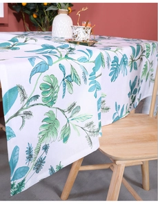 Detail of linen tablecloth featuring green tropical leaf prints and natural fabric texture