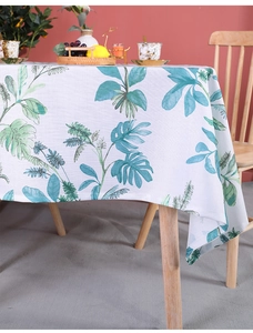 Close-up of tropical monstera leaf print on white cotton linen tablecloth fabric