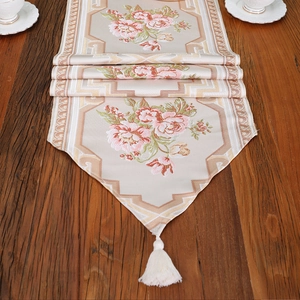 Floral bestickter Tischläufer mit rosa Rosen und Quasten auf dunklem Holzhintergrund