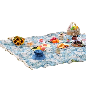 Blue floral yarn-dyed camping picnic mat with fringe tassels in a scenic outdoor setting