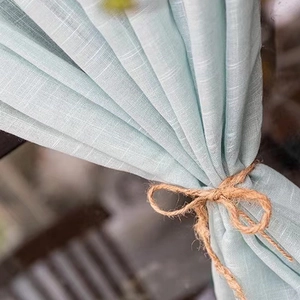 Linen texture light blue short curtain tied with fiber rope in natural sunlight