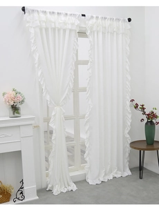 Detail of white velvet curtains featuring layered ruffle edges and rod pocket top design