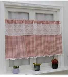 Detail of pink gingham cafe curtain with white floral lace and decorative pom pom trim
