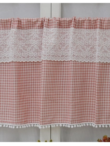 Macro shot of pink checkered cafe curtain featuring white lace trim and pompom fringe