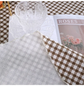 Detail of brown and white checkered cotton linen tablecloth with neat hemmed edges