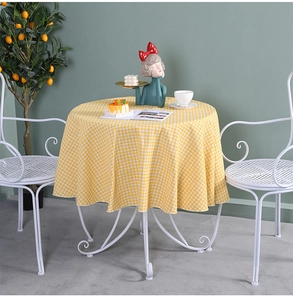 Detailed view of yellow gingham round tablecloth on white wrought iron bistro table