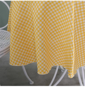 Detail of yellow and white gingham tablecloth with decorative wavy scalloped edges