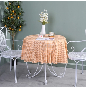 Detail of round orange gingham tablecloth showing fabric drape and home tea setting