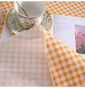 Detail of orange and white plaid cotton linen tablecloth with neat overlock edges