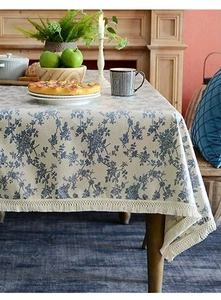 Détail de nappe en lin avec motifs floraux bleus et bordures à pompons élégantes