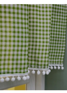 Detail of green and white plaid curtain fabric with white pom-pom fringe trim