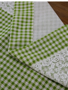 Detail of green gingham cafe curtain with delicate white lace trim on wooden background