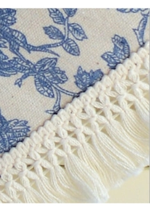 Détail d'une nappe en coton et lin beige avec motifs floraux bleus et bordure à franges