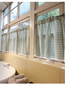 Detail of green and white plaid cafe curtain with white pom-pom trim and pleated header