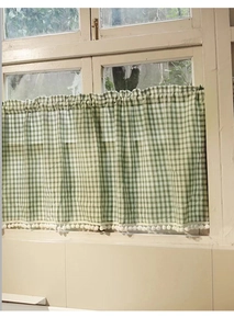 Detail of green gingham cafe curtain featuring white pom-poms on the bottom edge