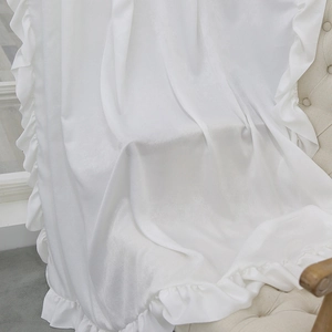 Elegant white velvet curtains with ruffle edges displayed on a luxury armchair