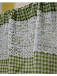 Detail of green plaid cotton fabric with white floral lace trim on a cafe curtain