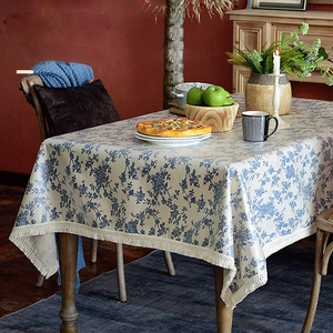 Nappe rectangulaire à fleurs nordiques avec pompons beige sur une table en bois rustique