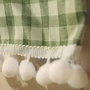 Green and white plaid cafe curtain with decorative white pom-pom fringe trim detail