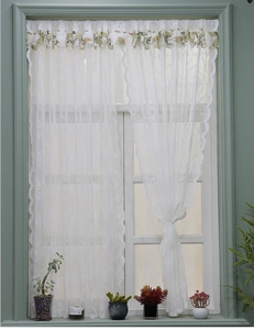 Détail du rideau en dentelle blanche avec broderie florale et cantonnière à feuilles