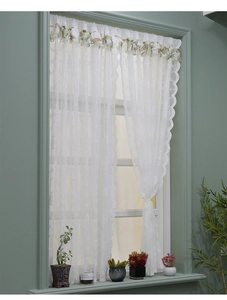 Détail du rideau en dentelle blanche avec volant floral vert et bords festonnés ondulés