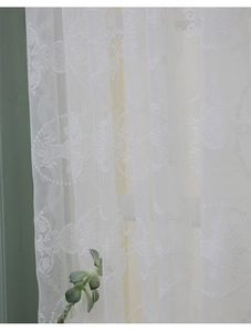 Détail de la broderie en dentelle florale blanche sur un rideau de fenêtre élégant