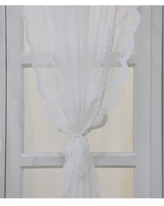 Détail du rideau en dentelle blanche avec motifs floraux et bords festonnés